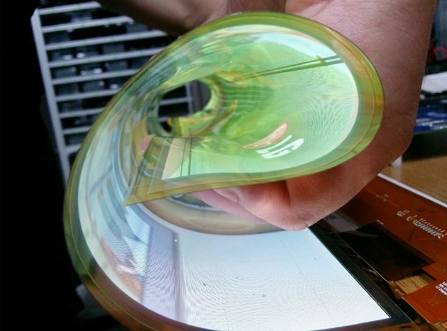 LG디스플레이 직원이 곡률반경 30R을 자랑하는 18인치 플렉시블 OLED를 말아서 시연해 보이고 있다.