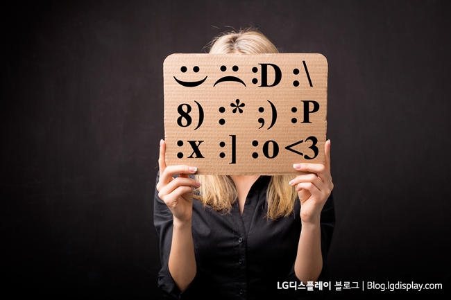 Woman holding cardboard with different emotion smileys in front of her face